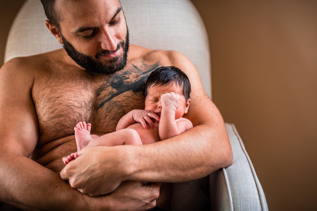 A father holds his newborn baby skin to skin in an image by Parkland, FL birth photographer Martha Lerner