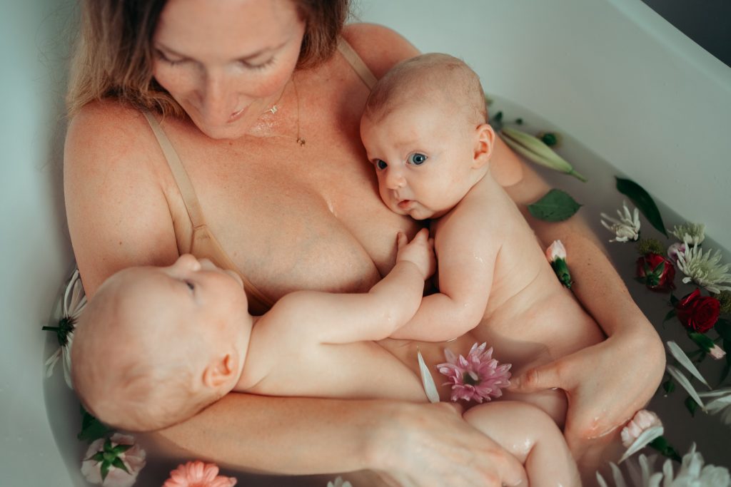 A mother in the tub holding her newborn twins.