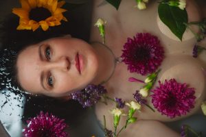 Woman floating in water surrounded by flowers