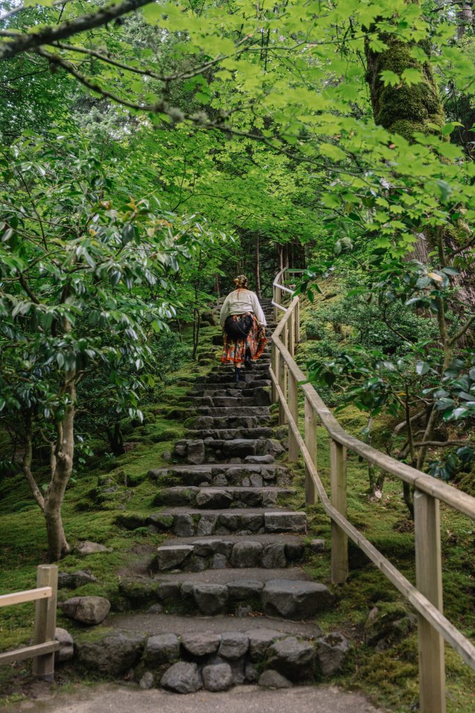 Woman walking up a stone staircase in nature.