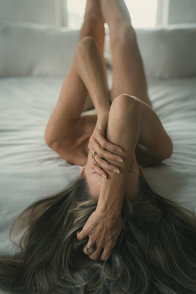 Woman lying on a bed running her fingers through her hair.