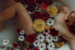 Woman in a tub full of flowers during an empowerment session