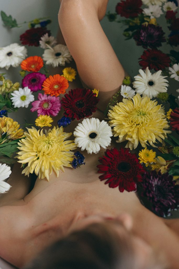 Woman in tub surrounded by flowers during an Empowerment Session