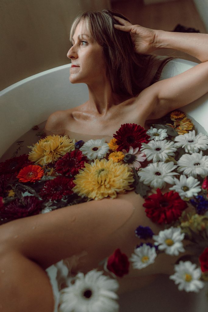 Woman surrounded by flowers in a bathtub during an Empowerment Session